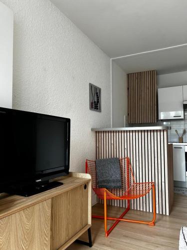 un salon avec une télévision à écran plat et une chaise dans l'établissement Superbe studio près de la plage, à La Grande Motte