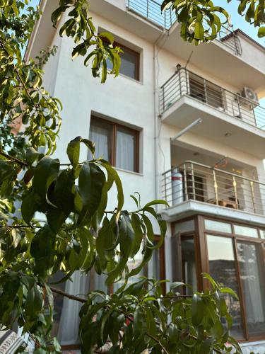 a white building with a balcony and a tree at Milas-Bodrum Özel Havuzlu Triplex Villa in Milas