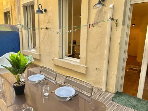 une table et des chaises sur une terrasse avec une fenêtre dans l'établissement Chez Marie et Romain- appartement de charme au cœur de la Joliette proche Panier centre ville, à Marseille