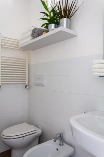 a white bathroom with a toilet and a sink at Cuore Flat in Modica