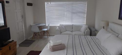 una camera bianca con un letto bianco e un divano di Amanda's Place a Hermanus