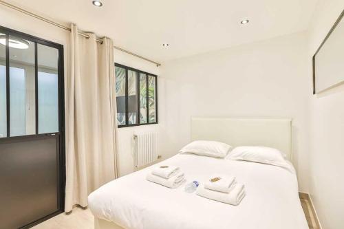 une chambre avec un lit blanc avec deux serviettes dessus dans l'établissement Newly renovated appartement ☆ Canal de L'ourq ☆, à Paris