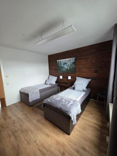 a bedroom with two beds and a wooden wall at Schwarzwald Lodge OG - Perfekt für Familien und Gruppen in Calw