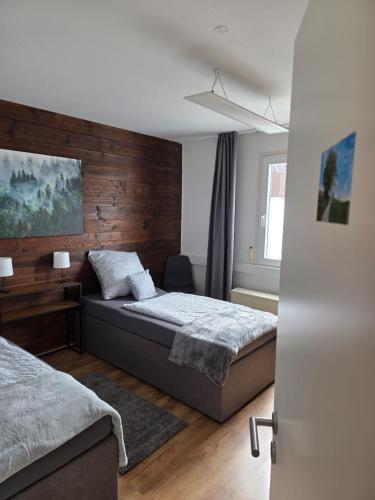 a bedroom with two beds and a wooden wall at Schwarzwald Lodge OG - Perfekt für Familien und Gruppen in Calw