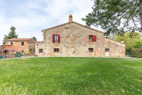 an old stone house with red windows and a yard at Podere Poggiolo in Trequanda