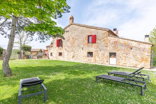 a stone house with two picnic tables in front of it at Podere Poggiolo in Trequanda