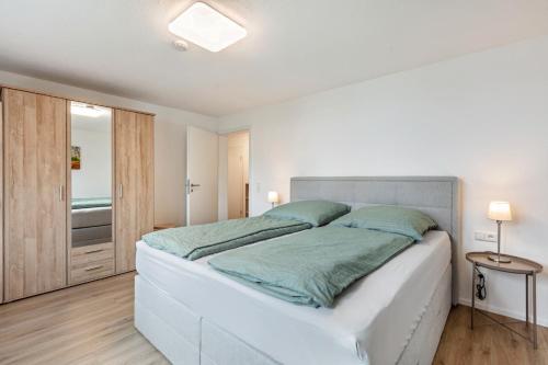 a white bedroom with a large white bed with blue pillows at Ferienwohnung K5 in Wehr