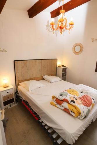 une chambre avec un grand lit blanc avec un lustre dans l'établissement Maison dans résidence avec piscine 3 Chambres, à Saint-Cyprien