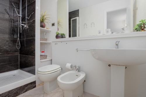 a white bathroom with a toilet and a sink at Casa Smeralda By Anthimea in Cugnana Verde