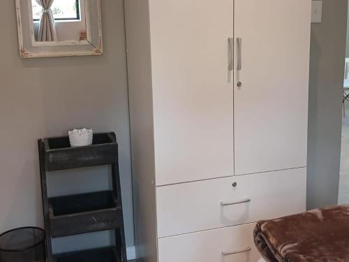 a bedroom with white cabinets and a mirror and a stool at Ledges Retreat in Bergville