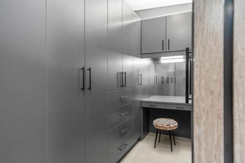 a kitchen with white cabinets and a stool and a counter at Red River Valley by Host Agents in Rooiels