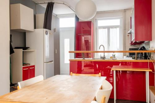 une cuisine avec des placards rouges et une table en bois dans l'établissement Family home: 3 bedrooms and a large garden!, à Lambersart