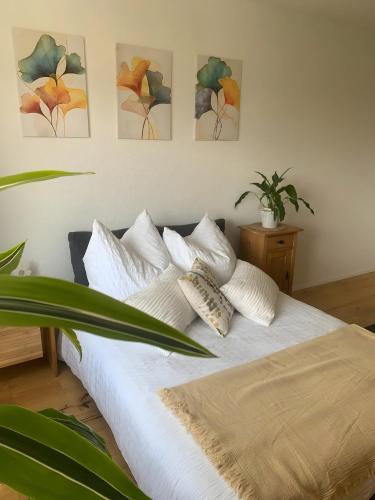 a bedroom with a white bed with four paintings on the wall at Gästehaus am See in Radolfzell am Bodensee