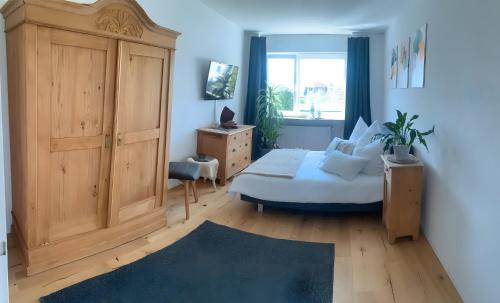 a bedroom with a bed and a wooden cabinet at Gästehaus am See in Radolfzell am Bodensee