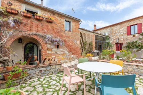 a patio with a table and chairs in front of a brick building at Podere Poggiolo in Trequanda