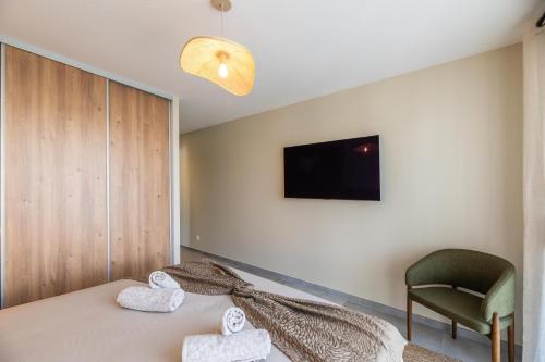 - une chambre avec un lit, une chaise et une télévision dans l'établissement VILLA VITRICCIA - VILLA DE REVE, PISCINE et PLAGE à 7MN A PIED !, à Zonza