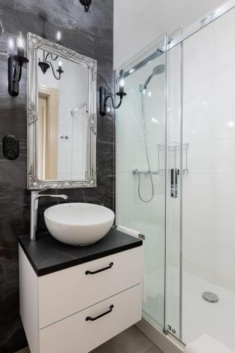 a bathroom with a sink and a glass shower at Loggia Apartments in Poznań