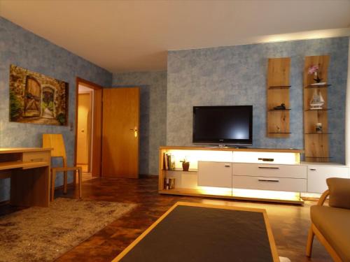 a living room with a television on a white cabinet at Ferienwohnung Mühlengrün in Oberwolfach