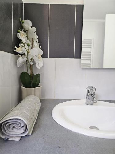 a bathroom with a sink and a vase with white flowers at Havre de Paix - Les Sablon d'A Côté in Amiens