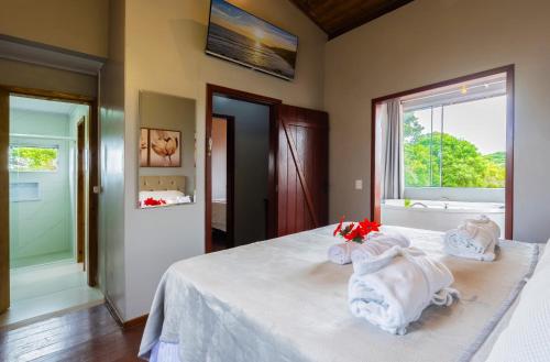 a bedroom with a bed with white sheets and a window at Pousada Natribus Rosa in Praia do Rosa