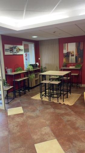 a room with tables and chairs and red walls at Hôtel Akena City Caudry in Caudry