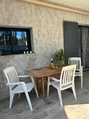 une table en bois, 2 chaises blanches, une table et des chaises dans l'établissement Bas de villa au calme absolu, à La Crau