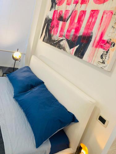 a bed with blue pillows and a painting on the wall at City Garden Loft in Pescara