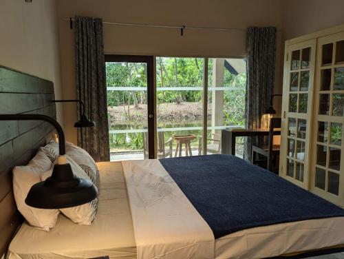 ein Schlafzimmer mit einem Bett und einem großen Fenster in der Unterkunft The Acadian Cottages in Madampe