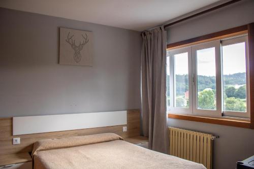 Val do DubraにあるApartamento Centro Bembibreのベッドと窓のある寝室