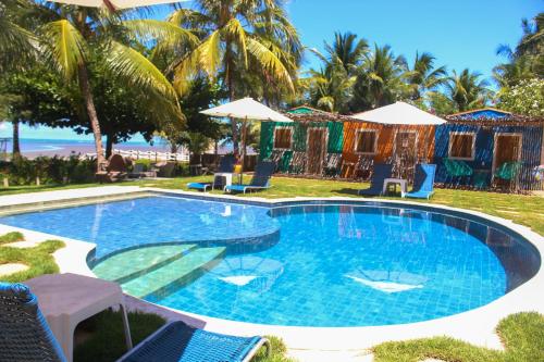 a large swimming pool with chairs and umbrellas at Pousada Villa Bougainville Maragogi in Maragogi