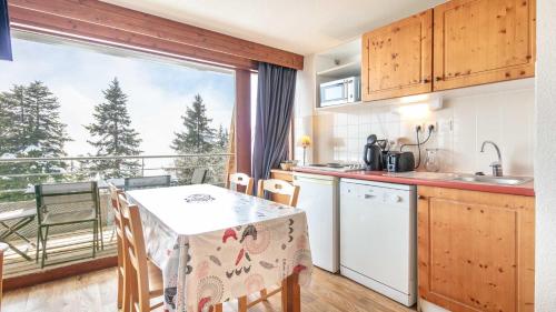 une cuisine avec une table et une vue sur un balcon dans l'établissement V du Bachat Arolles A n26 - 2P4, à Chamrousse