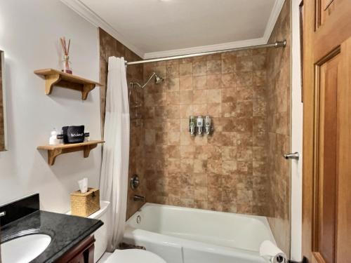 a bathroom with a tub and a toilet and a sink at CozyDen - AC, Grill, Bike to Mountain, Porch! in Killington