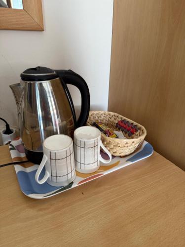 a tea kettle and three cups on a counter at Villa Lucija in Ohrid