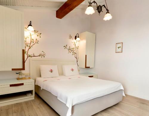 a white bedroom with a bed and two night stands at Sigacik Gardenya Buti̇k Otel in Siğacık