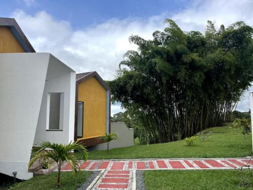 a house on a grassy field next to a tree at New Espectacular Chalet de lujo con vistas de lujo in Quindío