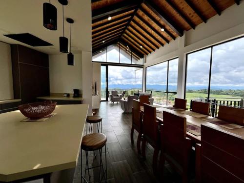 a kitchen with a counter and chairs and windows at New Espectacular Chalet de lujo con vistas de lujo in Quindío