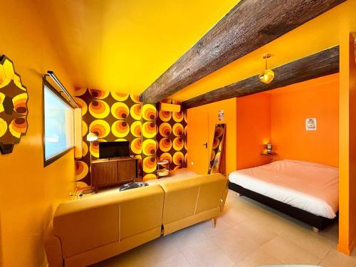 - une chambre avec des murs orange, un lit et une télévision dans l'établissement Studio 54 - Centre ville & Seventies, à Nîmes
