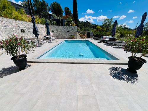 - une piscine avec deux plantes en pot sur une terrasse dans l'établissement Villa Coris, à Draguignan