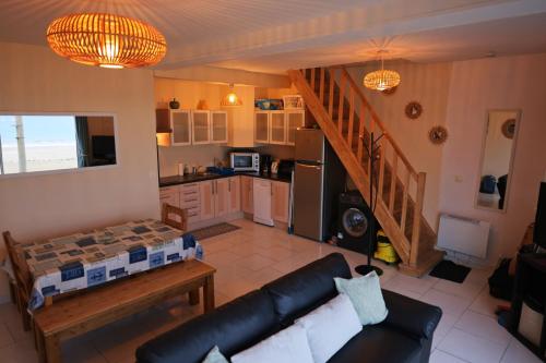 un salon avec un canapé et une cuisine dans l'établissement Maison pieds dans l'eau face mer, à Pléneuf-Val-André