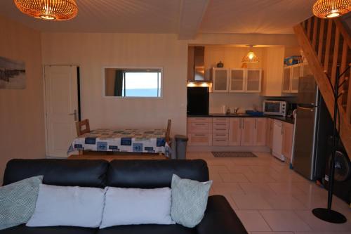 un salon avec un canapé et une cuisine dans l'établissement Maison pieds dans l'eau face mer, à Pléneuf-Val-André