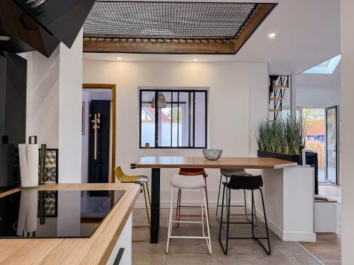 - une cuisine avec une table et des tabourets en bois dans l'établissement Maison avec jardin à 50m du Lac, à Ardres