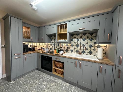 a kitchen with blue cabinets and a sink at House Sleeps 8-Garden-Parking Near Barry Island in Flemingston