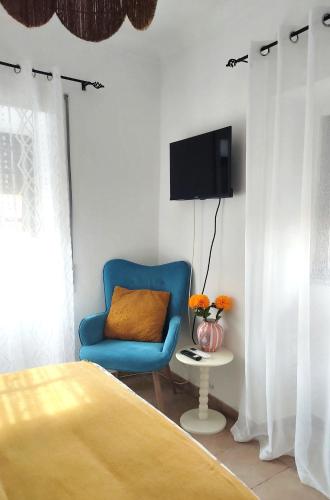 a bedroom with a blue chair and a tv on a wall at Catespero Sossego in Reguengos de Monsaraz