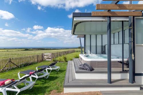 a glass house with a bed and two chairs at The house of the guardians of the Ocean with spa - gite plougonvelin in Plougonvelin