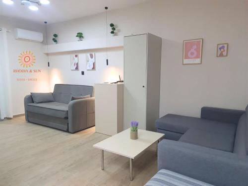 a living room with two blue couches and a table at Rhódia & Sun by Booking Kottas in Ixia