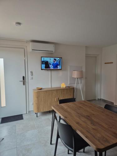 LecciにあるLes hameaux de Saint Cyprien - appartement avec jardin et piscineのテーブルと椅子、壁にテレビが備わる客室です。