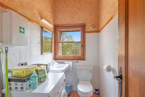 a bathroom with a toilet and a sink and a window at El Molí De Canellas in Sagás