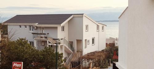 a white house on a hill next to the ocean at Apartmani ANDRIJA in Živogošće