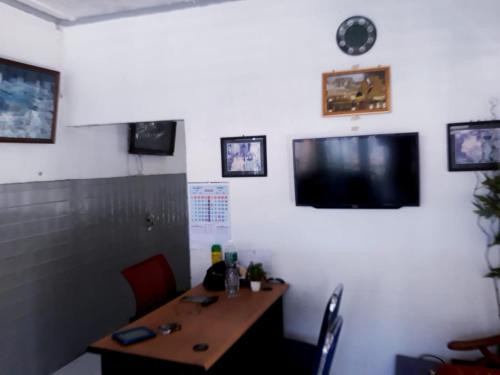 a dining room with a table and a tv on the wall at Wisma Syariah Rumah Bundo in Padang