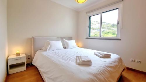 a bedroom with a white bed with a window at Pestana Green View in Caniço